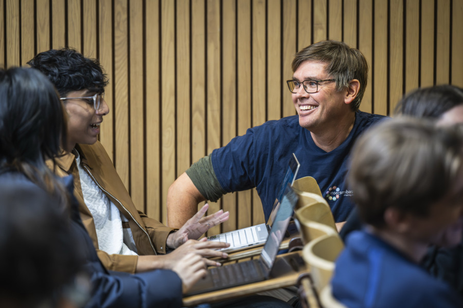 Sean Schoville kneels next to a student during class to better understand and answer a question.